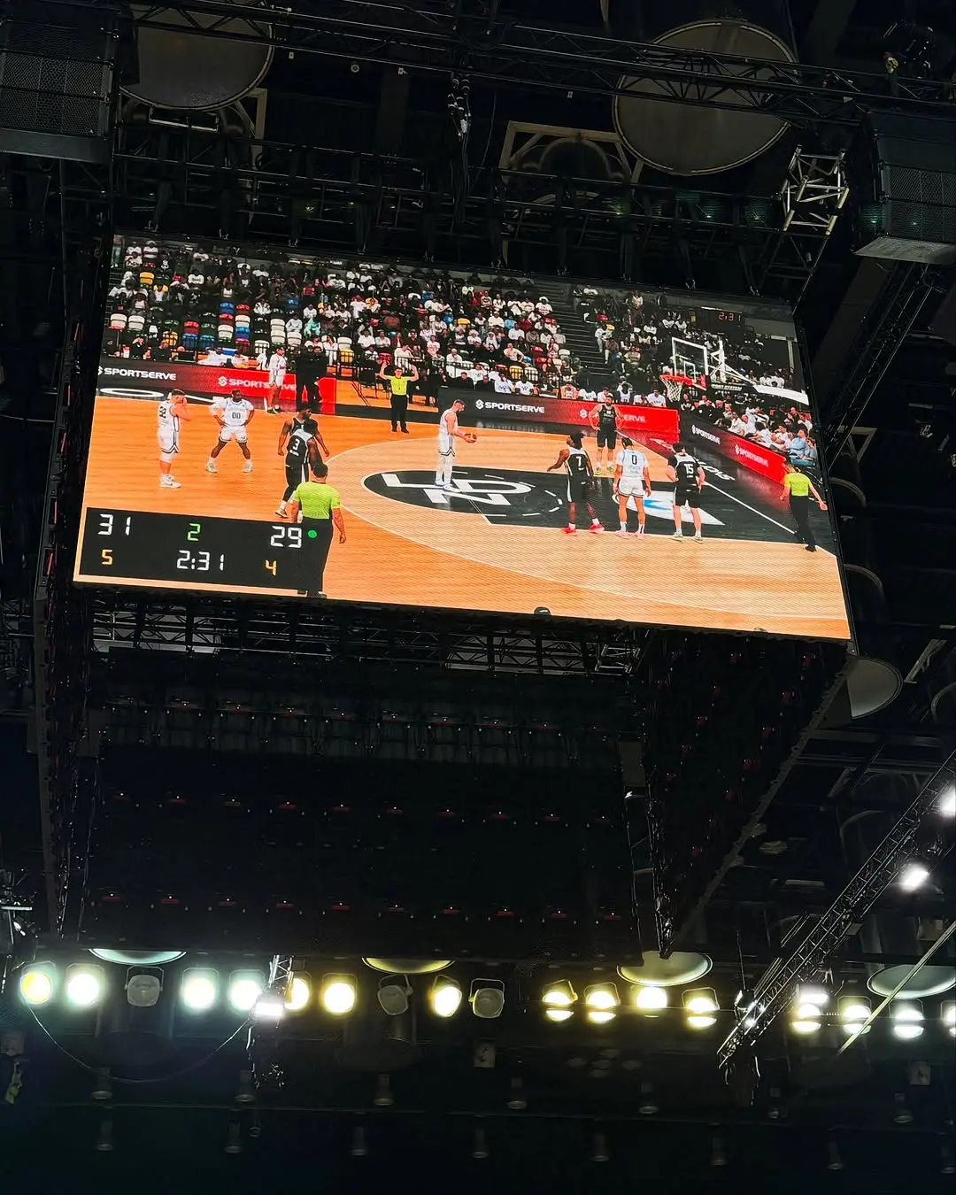 Large LED video screen showing live basketball game feed at Copper Box Arena with professional AV production and lighting rig