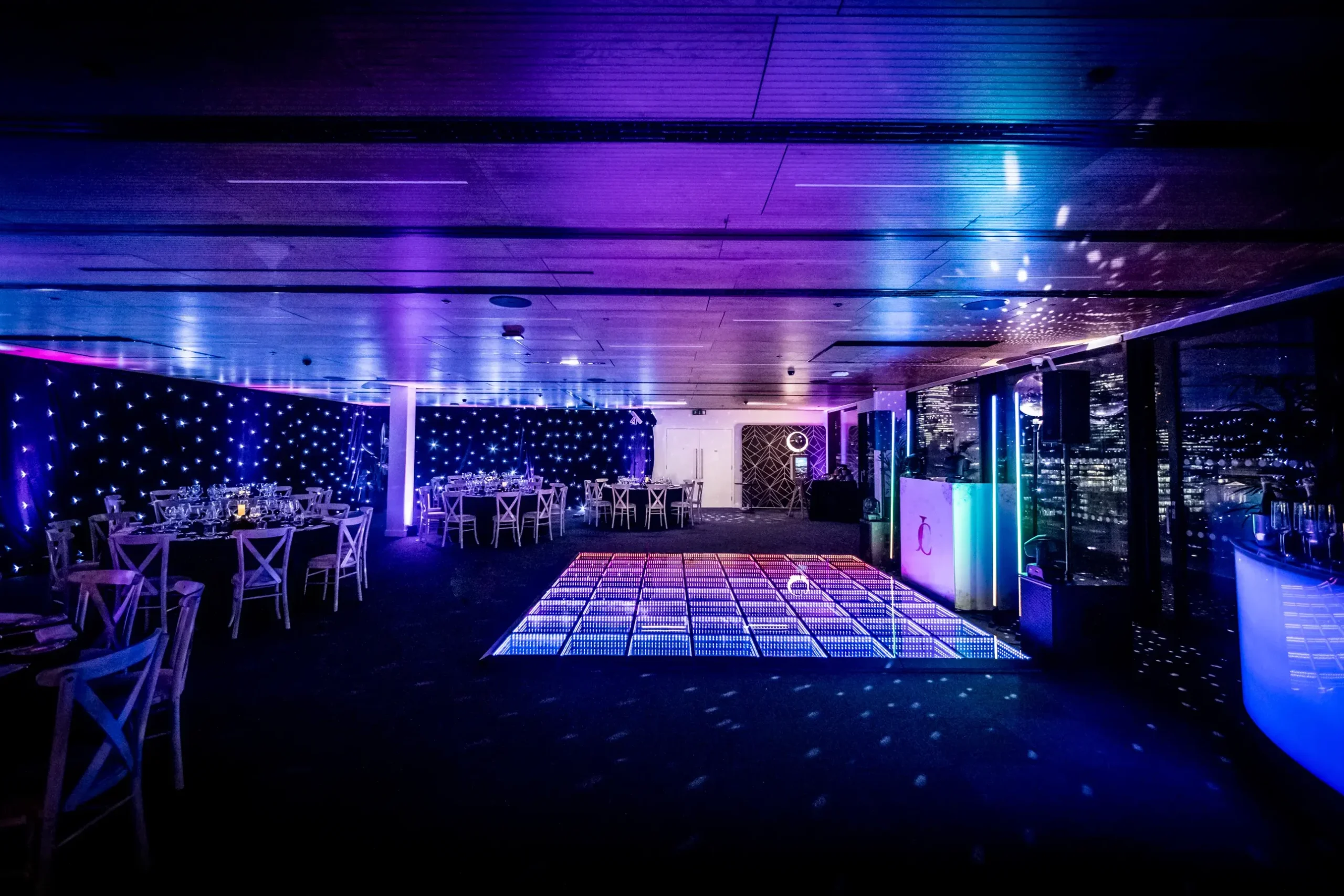 Rose Court transformed for corporate party with LED dancefloor, DJ booth, starlit draping and dynamic event lighting