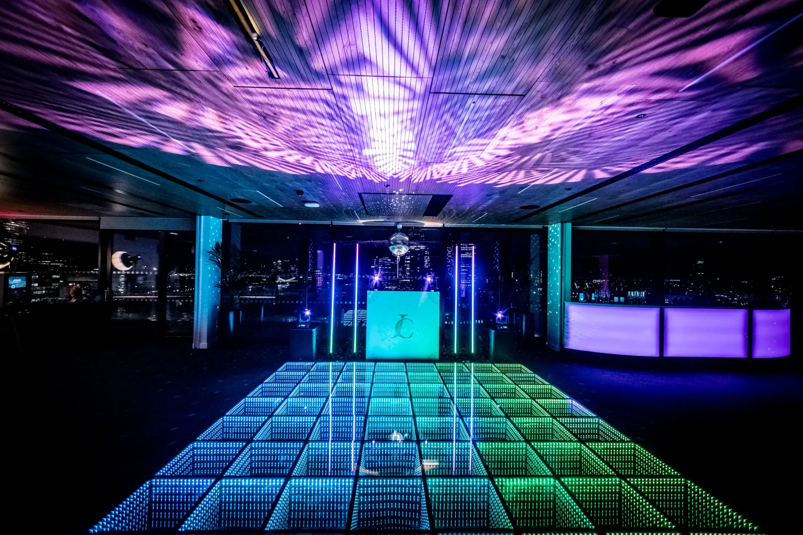 Rose Court corporate event transformation with LED dancefloor, custom DJ booth, skyline backdrop and dynamic ceiling lighting