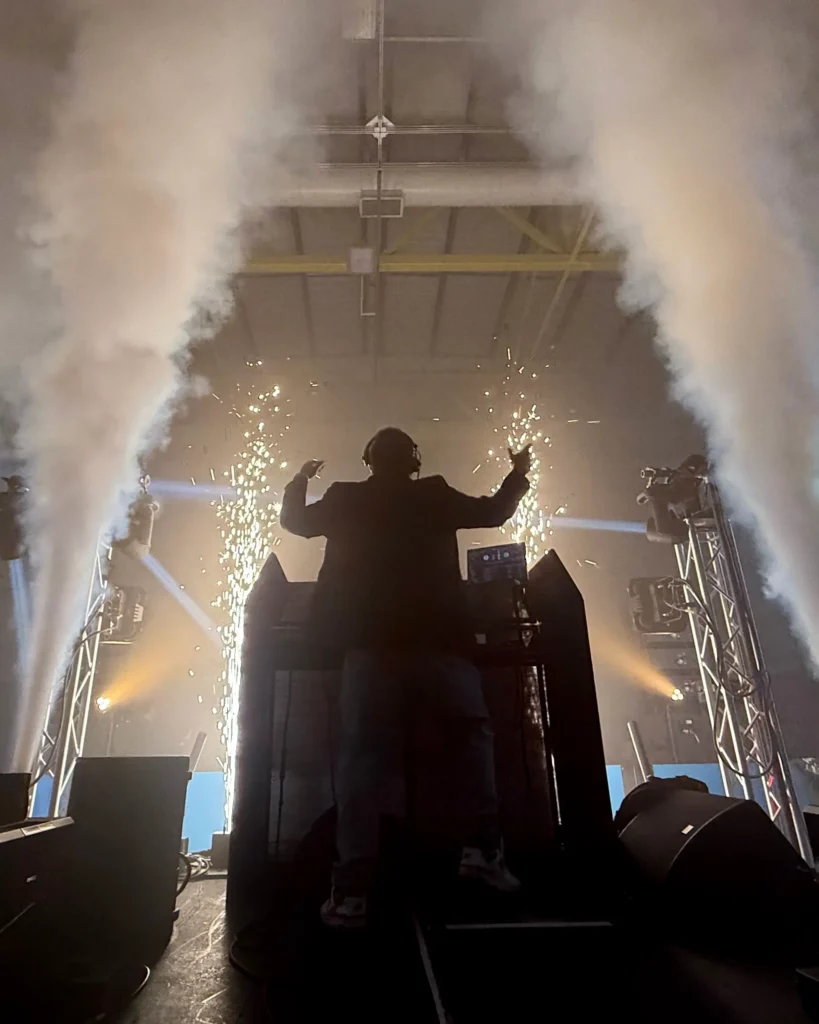 Corporate event DJ performing on stage with special effects, CO2 jets, and professional event production lighting