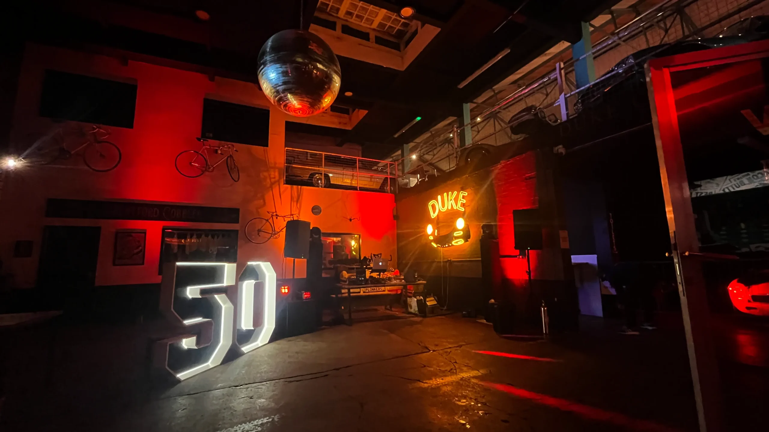 Wireless uplighting and event production at Duke of London private hire venue with DJ setup and warm architectural lighting