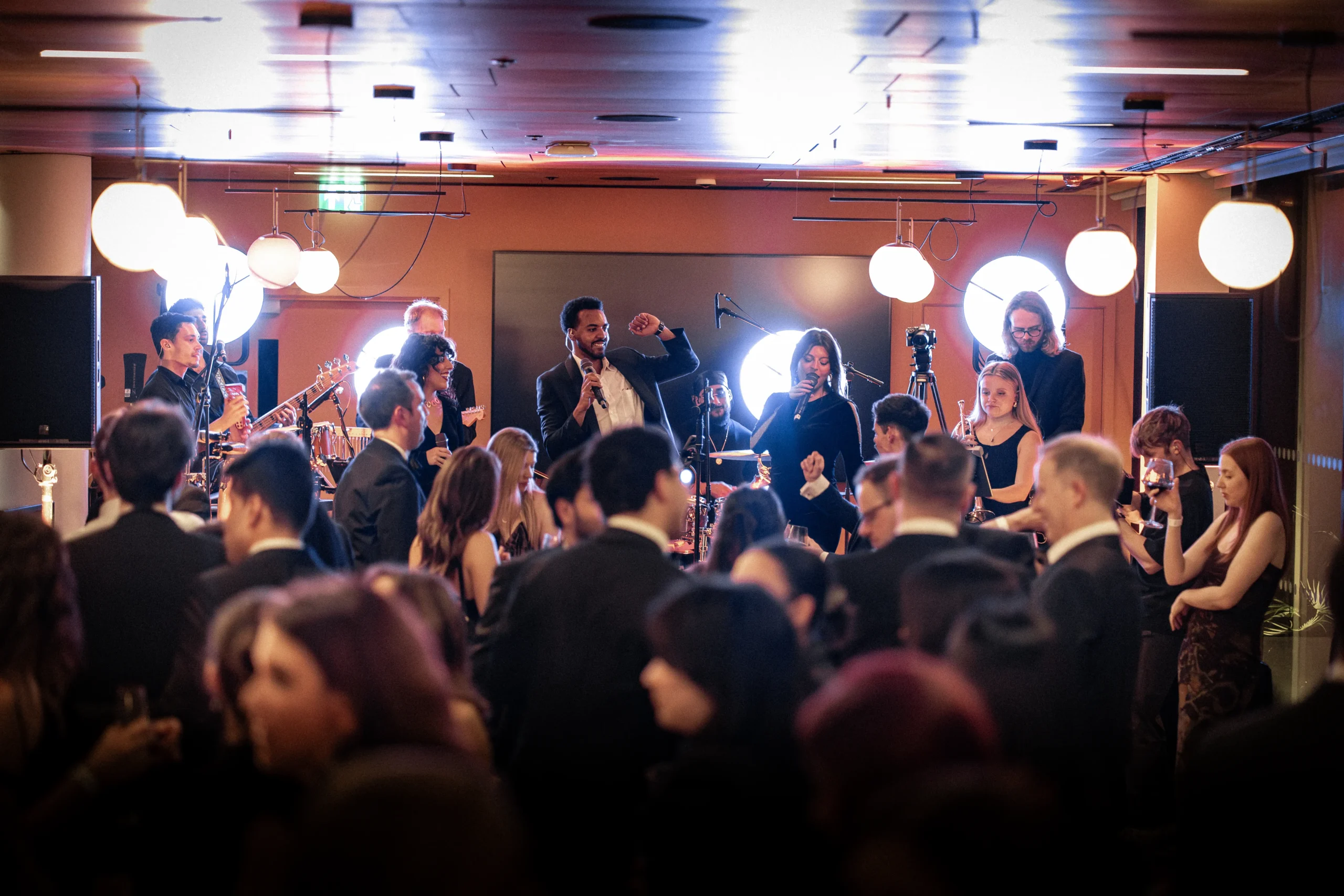 Live band performance at a corporate event with singers and musicians on stage entertaining guests at an evening reception.