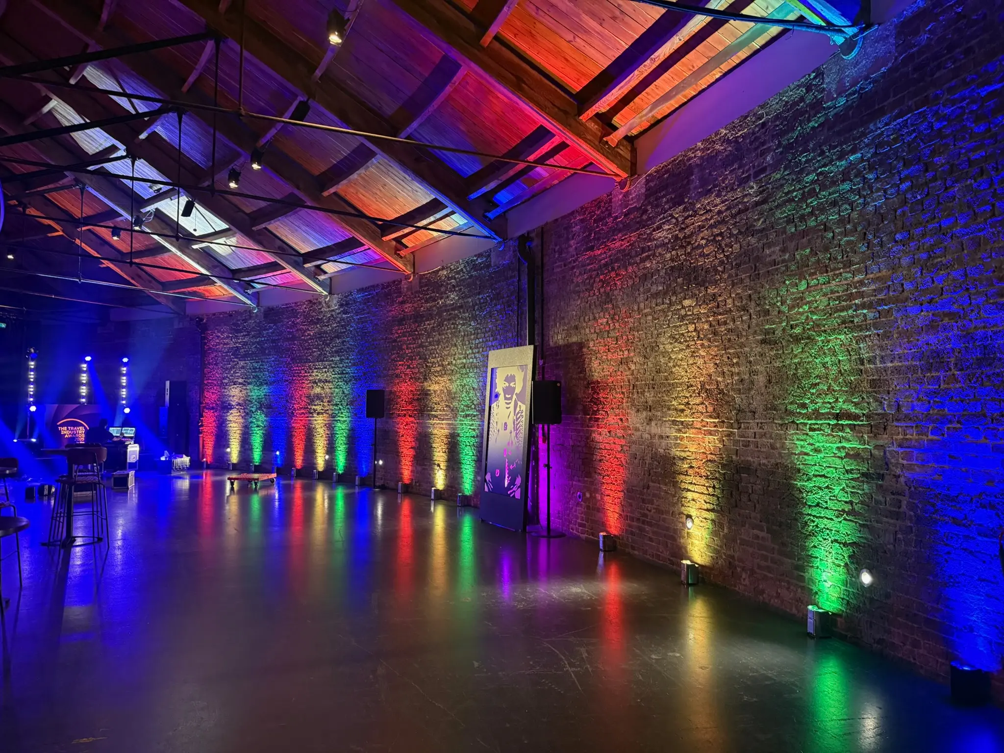 Wireless uplighters creating colourful wall wash lighting at London corporate event venue