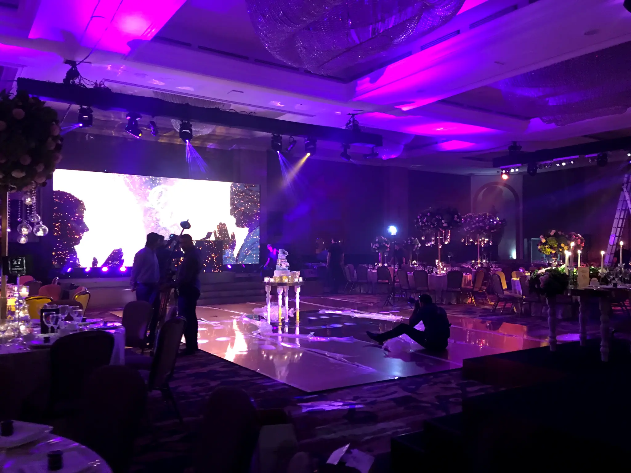 Mirrored dancefloor at wedding reception with stage lighting and large LED screen backdrop