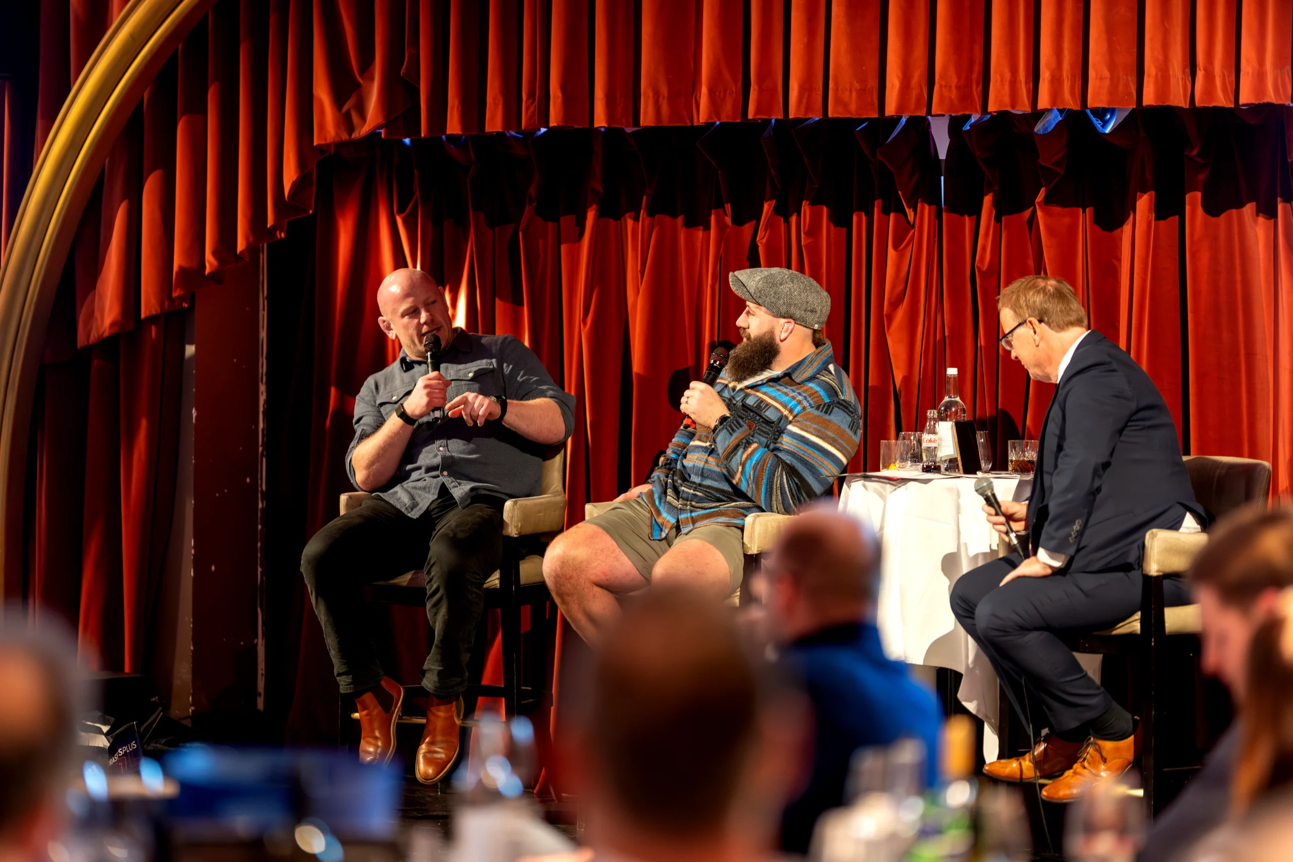 Corporate hospitality AV London speaker setup with stage seating, wireless microphone and premium venue styling