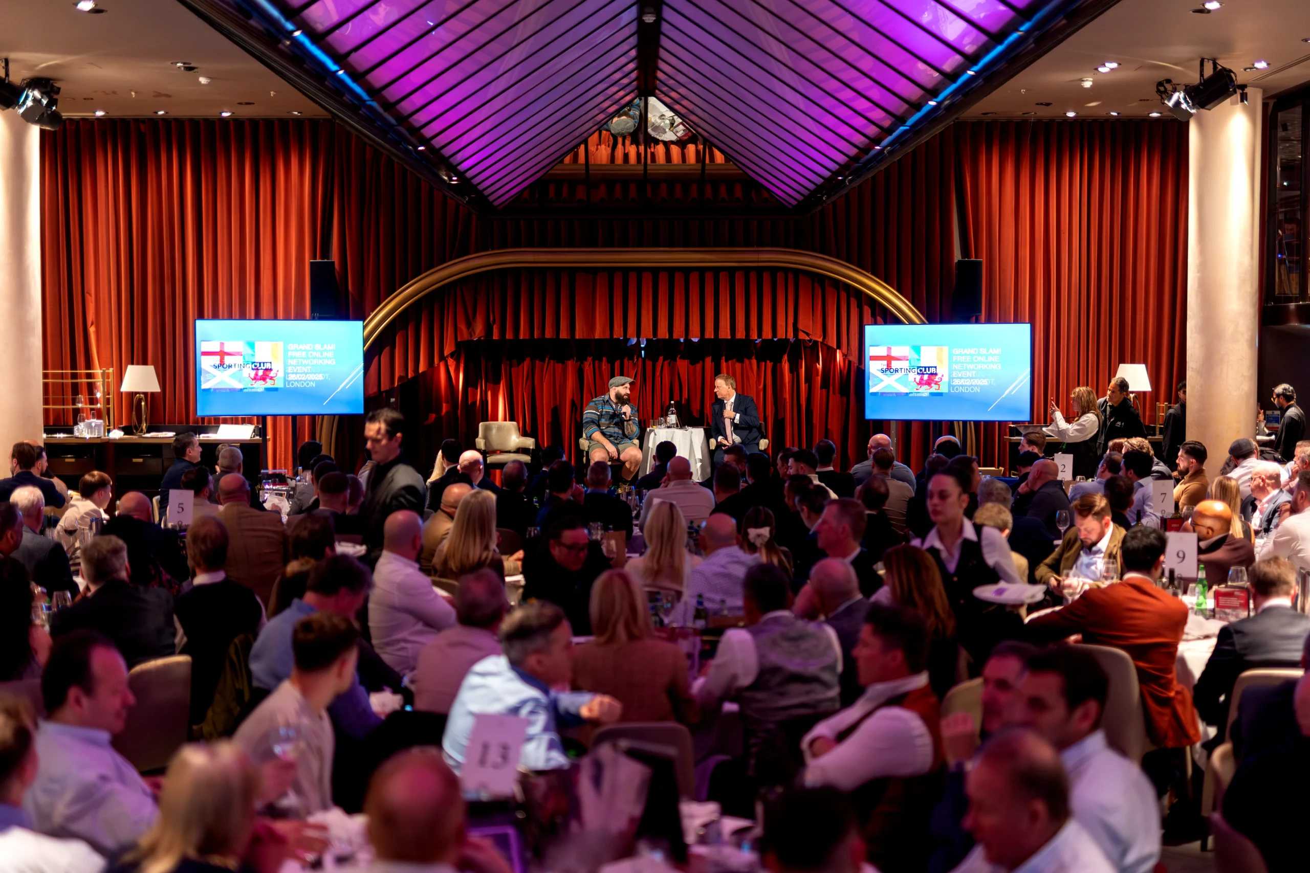 Wide shot of premium hospitality venue with staged speaker setup and audience seating
