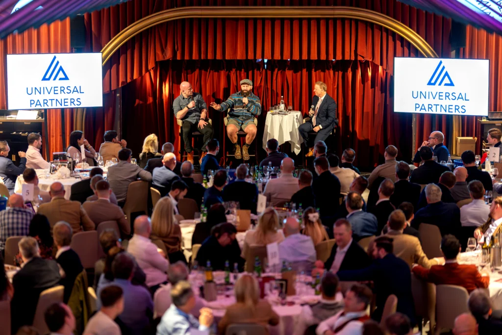 Wide hero image of premium hospitality event with live speaker session and audience