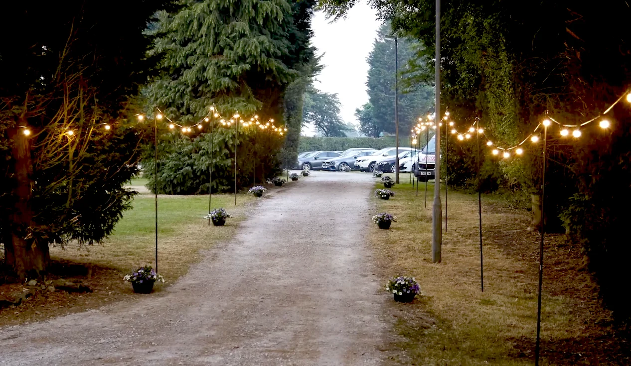 Festoon lighting installed along a garden pathway for an outdoor event
