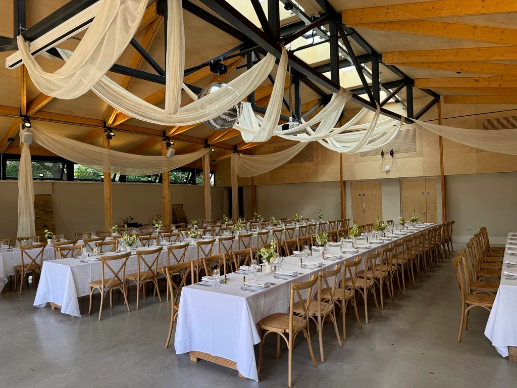 Wedding reception with ceiling draping and mirror ball in a modern London venue.